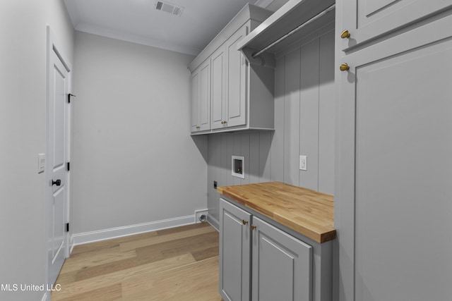 washroom featuring hookup for a washing machine, light wood-style floors, electric dryer hookup, cabinet space, and baseboards