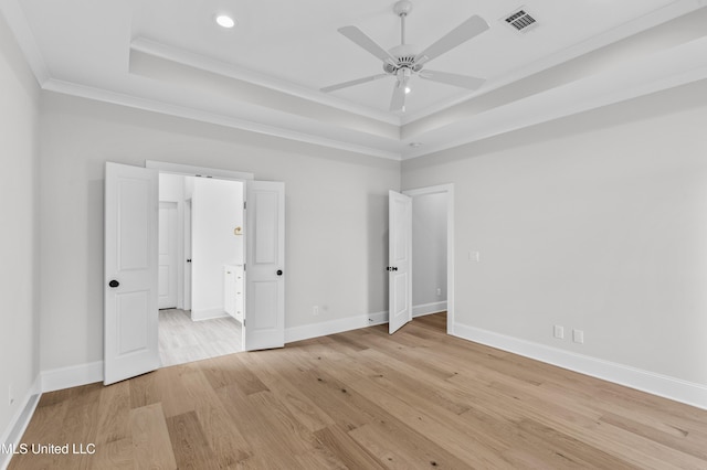 unfurnished bedroom with a raised ceiling, light wood-type flooring, crown molding, recessed lighting, and baseboards