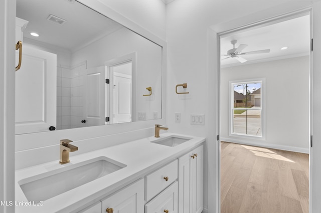 bathroom with wood finished floors, ceiling fan, double vanity, recessed lighting, and baseboards