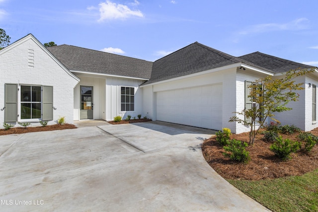 view of front facade featuring a shingled roof, brick siding, a garage, and driveway