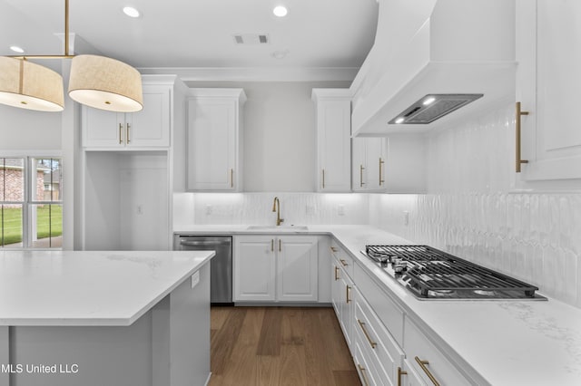 kitchen featuring appliances with stainless steel finishes, a sink, white cabinets, dark wood-type flooring, and backsplash