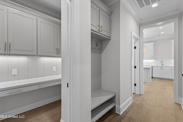 mudroom featuring crown molding, light wood-style flooring, a sink, baseboards, and recessed lighting