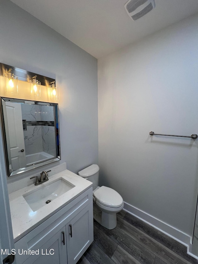 bathroom featuring visible vents, a shower, toilet, wood finished floors, and vanity