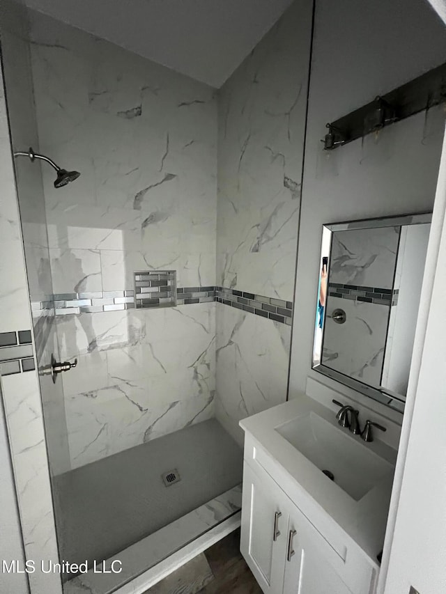 full bath featuring vanity and a marble finish shower