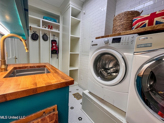 laundry area featuring sink, tile patterned floors, and washing machine and clothes dryer