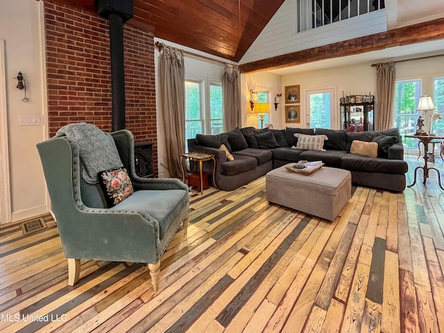 living room with light hardwood / wood-style floors, a wood stove, high vaulted ceiling, and plenty of natural light