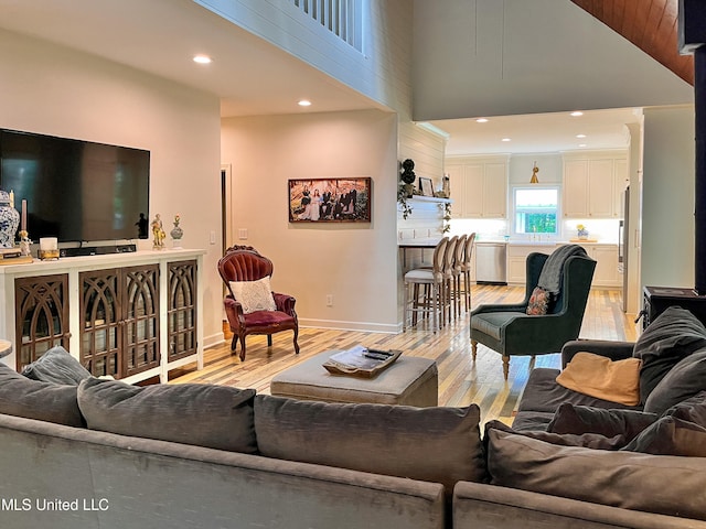 living room with light hardwood / wood-style floors and a towering ceiling