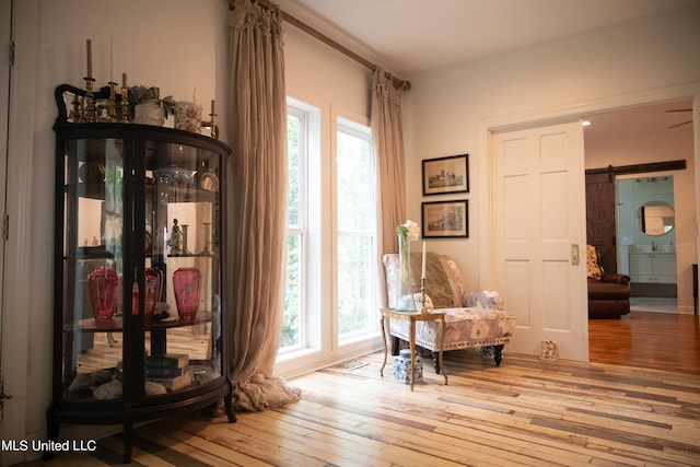 sitting room with a barn door and light wood-type flooring