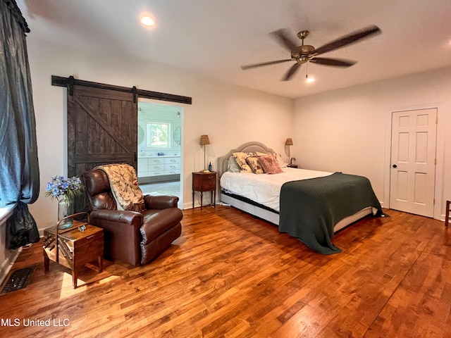 bedroom with hardwood / wood-style floors, a barn door, and ceiling fan