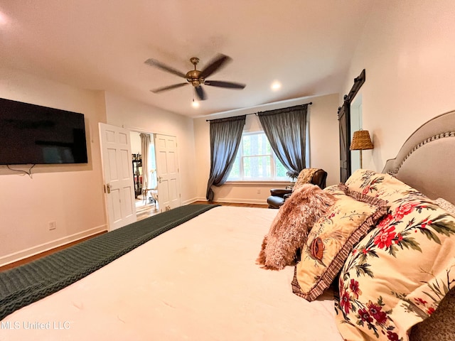 bedroom with a barn door and ceiling fan