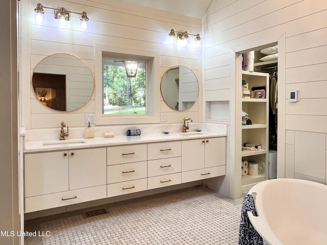 bathroom featuring wood walls, vanity, tile patterned flooring, and a washtub