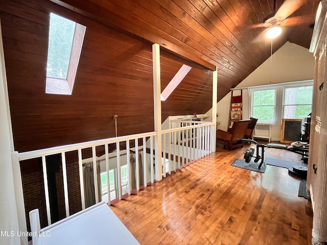 additional living space with vaulted ceiling with skylight, hardwood / wood-style floors, wooden ceiling, and ceiling fan