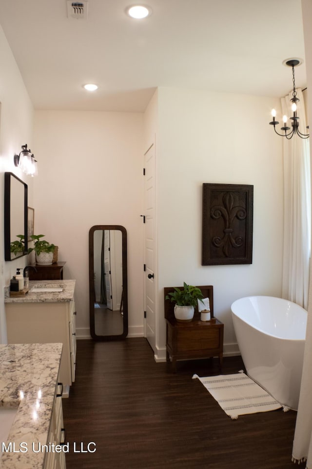 691 Apona St, Diamondhead, MS 39525 - bathroom with vanity, wood finished floors, a soaking tub, a chandelier, and baseboards