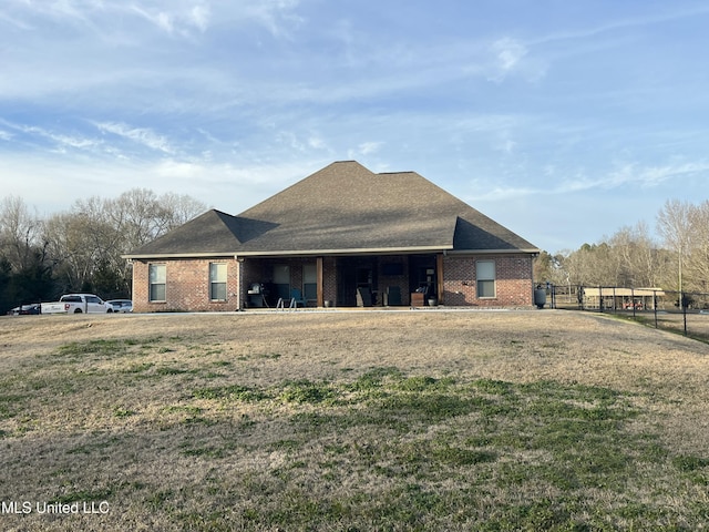 back of house featuring brick siding, roof with shingles, and fence