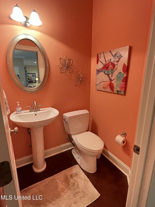 half bathroom featuring a sink, toilet, and baseboards