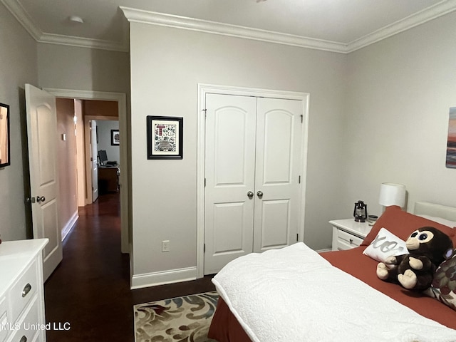 bedroom with dark wood-style floors, ornamental molding, a closet, and baseboards