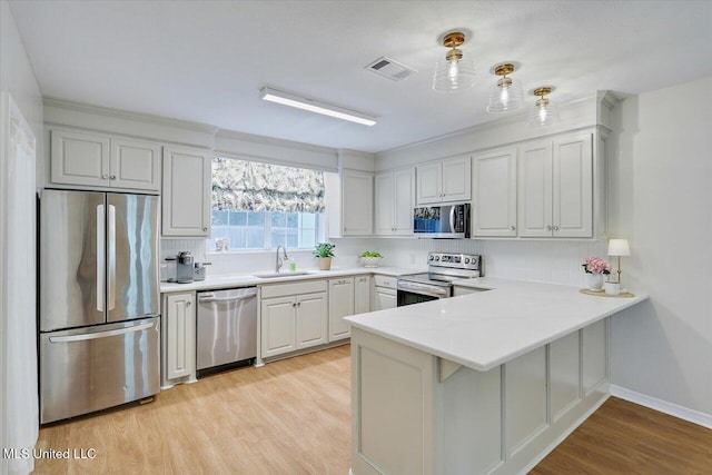 322 NW 2nd Ave, Magee, MS 39111 - kitchen featuring stainless steel appliances, a peninsula, light wood-style flooring, and light countertops