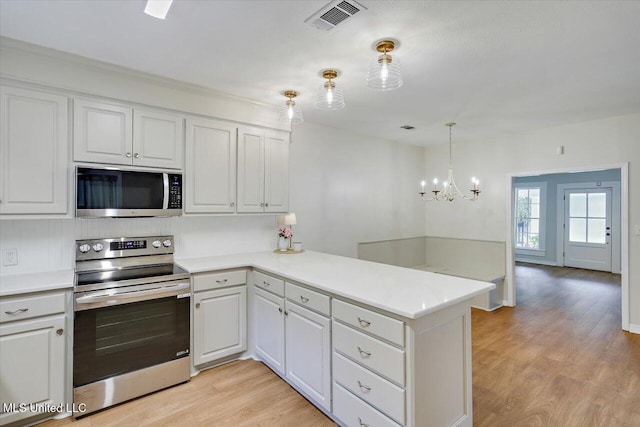 322 NW 2nd Ave, Magee, MS 39111 - kitchen featuring appliances with stainless steel finishes, a peninsula, light wood-style floors, and white cabinets