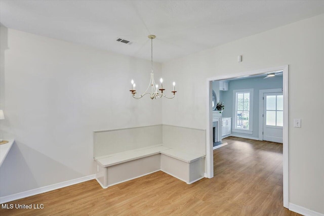 322 NW 2nd Ave, Magee, MS 39111 - unfurnished dining area featuring light wood-style floors, a chandelier, and a fireplace with raised hearth