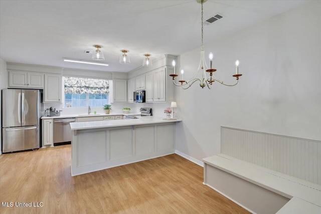 322 NW 2nd Ave, Magee, MS 39111 - kitchen with appliances with stainless steel finishes, light countertops, a peninsula, light wood-type flooring, and a chandelier