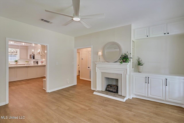 322 NW 2nd Ave, Magee, MS 39111 - unfurnished living room featuring a ceiling fan, light wood-type flooring, a brick fireplace, and a chandelier