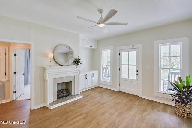 322 NW 2nd Ave, Magee, MS 39111 - unfurnished living room with light wood finished floors, a ceiling fan, and a fireplace