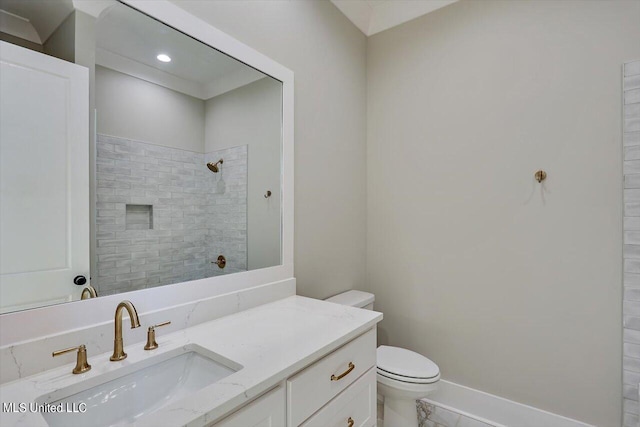 bathroom with vanity, toilet, and a tile shower