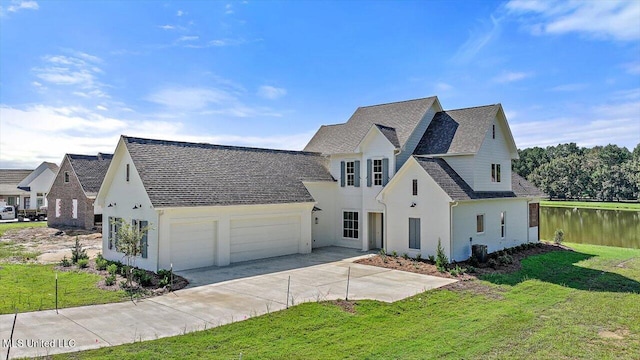 view of front of house with a front yard, a garage, and a water view