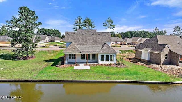 rear view of house featuring a water view and a lawn