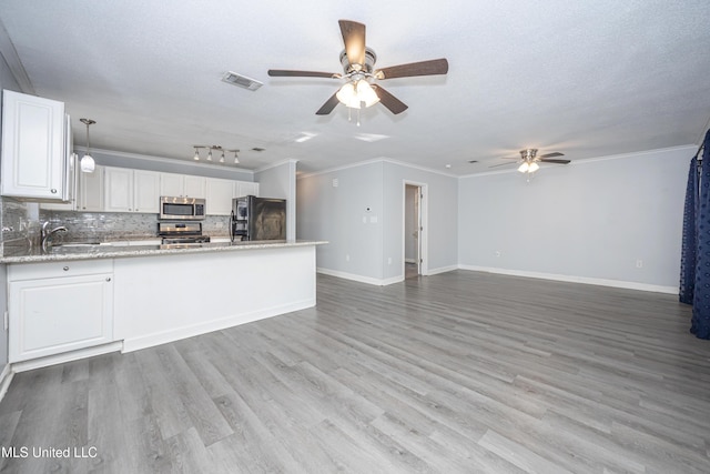 kitchen featuring white cabinetry, stainless steel appliances, tasteful backsplash, hanging light fixtures, and crown molding