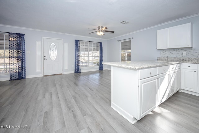 kitchen featuring white cabinets, kitchen peninsula, ornamental molding, and light hardwood / wood-style flooring