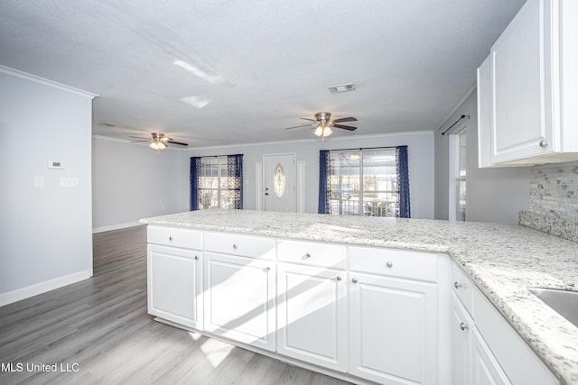 kitchen with light stone counters, white cabinetry, and a healthy amount of sunlight