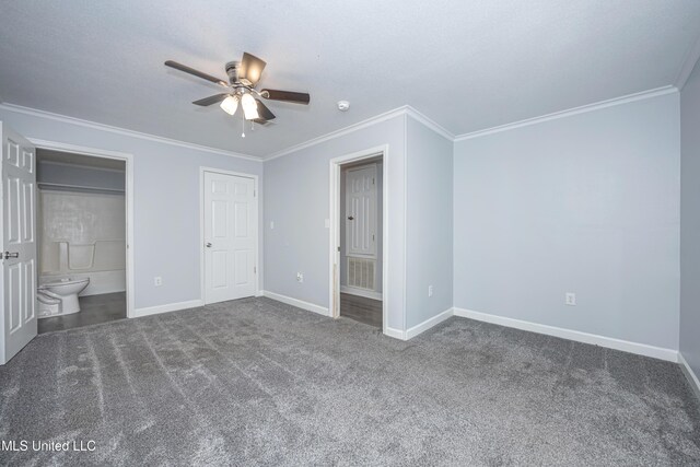 unfurnished bedroom with ceiling fan, dark carpet, connected bathroom, and ornamental molding