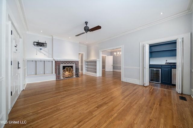 905 Franklin St, Corinth, MS 38834 - unfurnished living room with a ceiling fan, wood finished floors, a fireplace, crown molding, and a chandelier