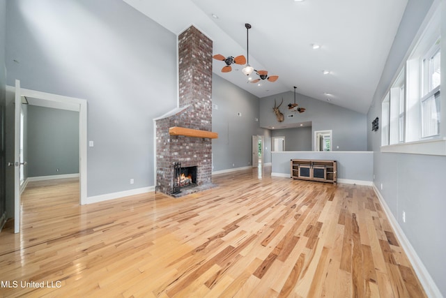 905 Franklin St, Corinth, MS 38834 - unfurnished living room featuring high vaulted ceiling, wood finished floors, a brick fireplace, healthy amount of natural light, and baseboards