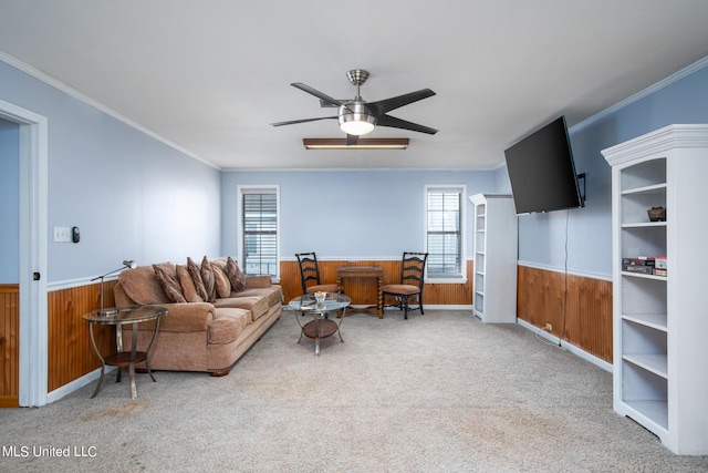 living room with a wainscoted wall, wooden walls, carpet flooring, and crown molding