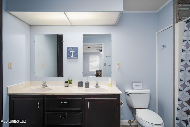 full bath with a sink, toilet, double vanity, and crown molding