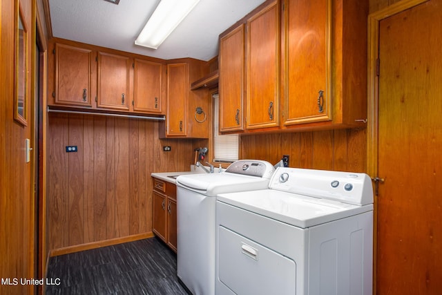 laundry room with a sink, cabinet space, wood walls, and washing machine and clothes dryer