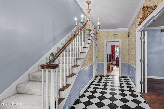 staircase with an inviting chandelier and ornamental molding