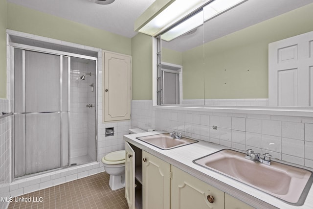 bathroom with walk in shower, tile walls, toilet, vanity, and tile patterned flooring