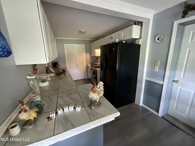260 SCR 62, Magee, MS 39111 - kitchen featuring black fridge with ice dispenser, gas range oven, ornamental molding, white cabinetry, and baseboards