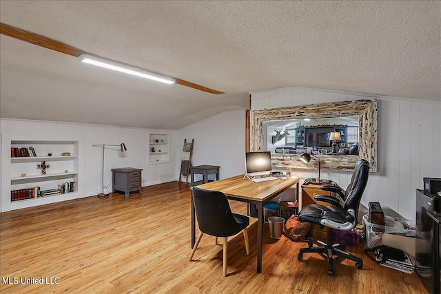 office area featuring light hardwood / wood-style floors, a textured ceiling, built in features, and vaulted ceiling