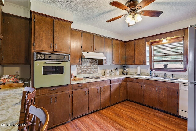 kitchen with white appliances, crown molding, a textured ceiling, light hardwood / wood-style floors, and ceiling fan