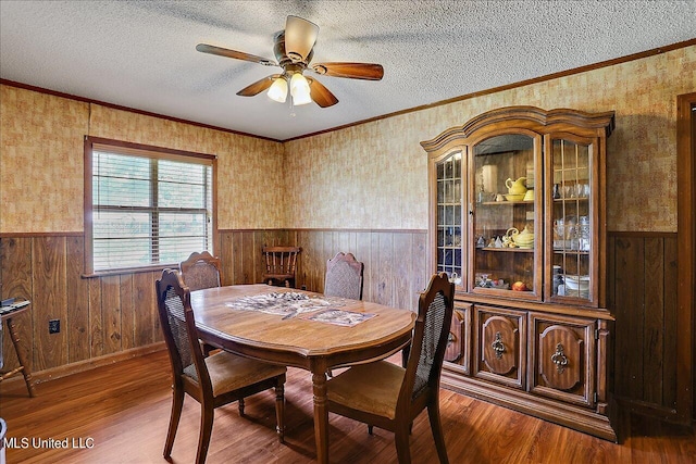 dining room with ceiling fan, a textured ceiling, ornamental molding, and hardwood / wood-style floors