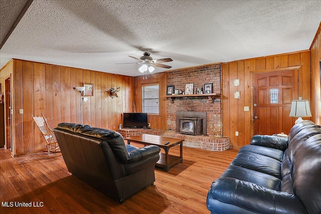 living room featuring light hardwood / wood-style floors, a textured ceiling, and a wood stove