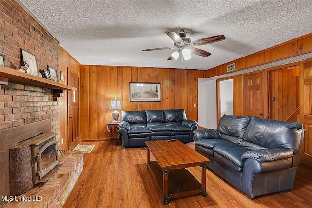 living room featuring wood walls, hardwood / wood-style flooring, crown molding, a textured ceiling, and ceiling fan