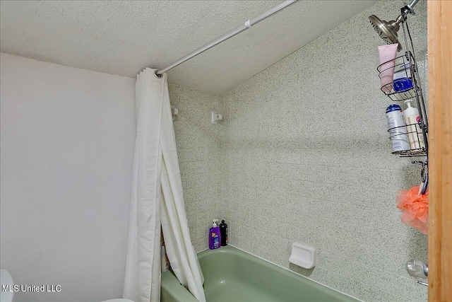 bathroom with shower / bath combination with curtain and a textured ceiling