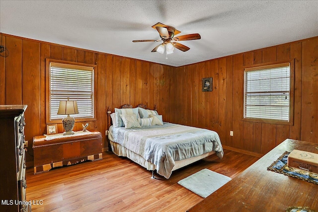 bedroom with ceiling fan, a textured ceiling, multiple windows, and light wood-type flooring