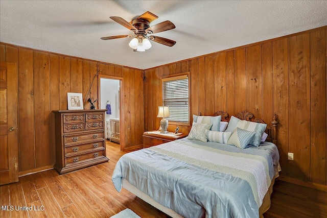 bedroom with wood walls, light hardwood / wood-style floors, and ceiling fan