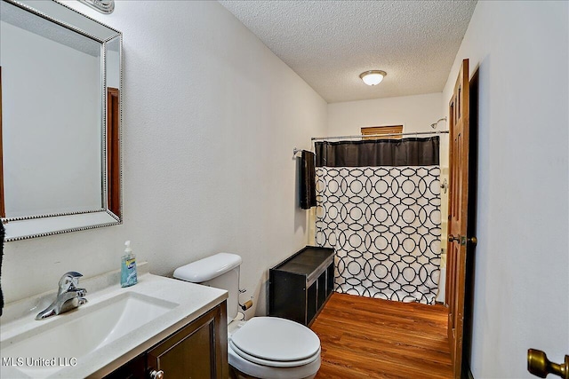 bathroom with a textured ceiling, hardwood / wood-style flooring, toilet, vanity, and a shower with curtain